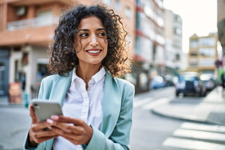 Young business woman wearing professional look smiling confident at the city using smartphone