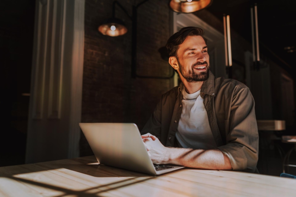 Man working at a computer, smiling and laughing off to the side