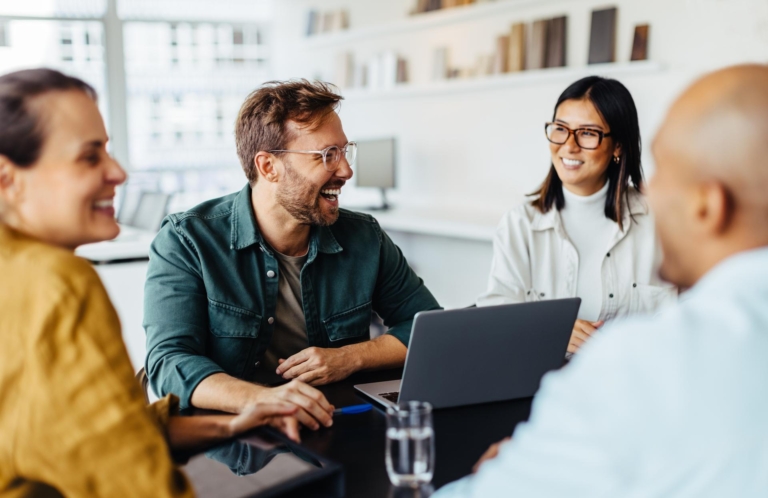 Group of happy business professionals sitting around a table and having a discussion.